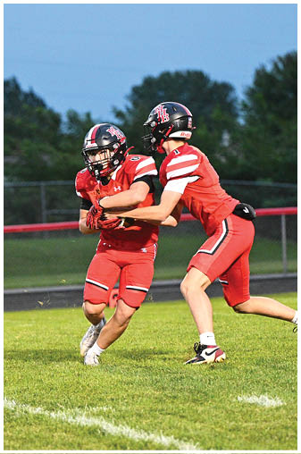 Two football players running on a field. Description generated by AI