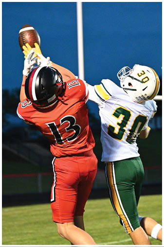 A football player in a red jersey catching a ball. Description generated by AI