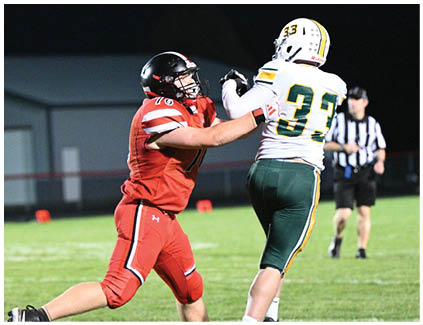 A man in a red jersey is trying to block a football player. Description generated by AI