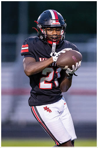 A football player in a black jersey with the number 6 on it. Description generated by AI