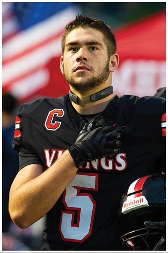 A man running on a field with a football jersey on. Description generated by AI
