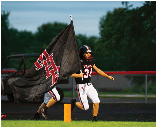 A football player in a yellow jersey is tackled to the ground. Description generated by AI