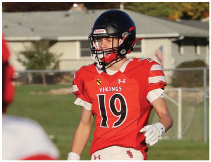 A football player wearing a white jersey and black shorts catching a football. Description generated by AI
