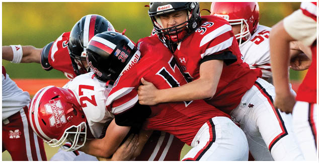 A football player in a yellow jersey is tackled by another player. Description generated by AI
