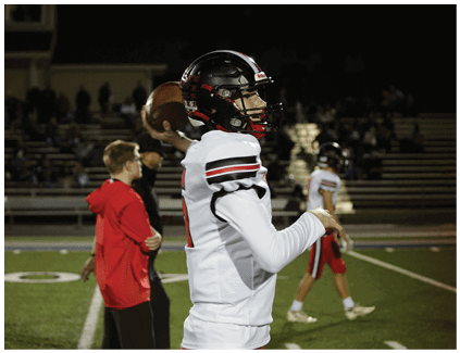 A football player wearing a black and white jersey with the number 12 on it. Description generated by AI