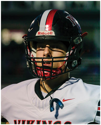 A football player in a black jersey is running with a football. Description generated by AI