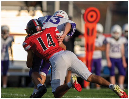 A football player wearing a white jersey and black shorts catching a football. Description generated by AI