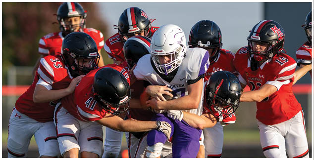A football player in a yellow jersey is tackled by another player. Description generated by AI