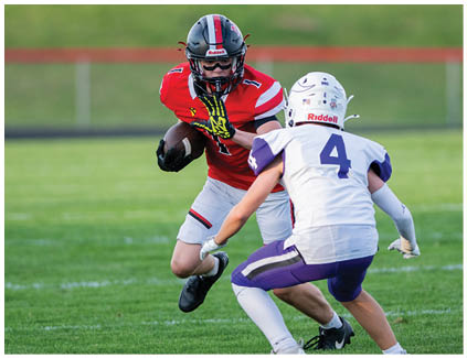 A football player wearing a white jersey and black shorts catching a football. Description generated by AI