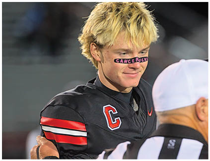 A football player wearing a black and white jersey with the number 12 on it. Description generated by AI