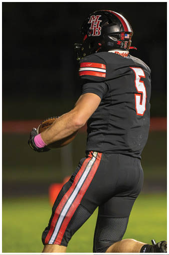 A football player in a black jersey with the number 6 on it. Description generated by AI