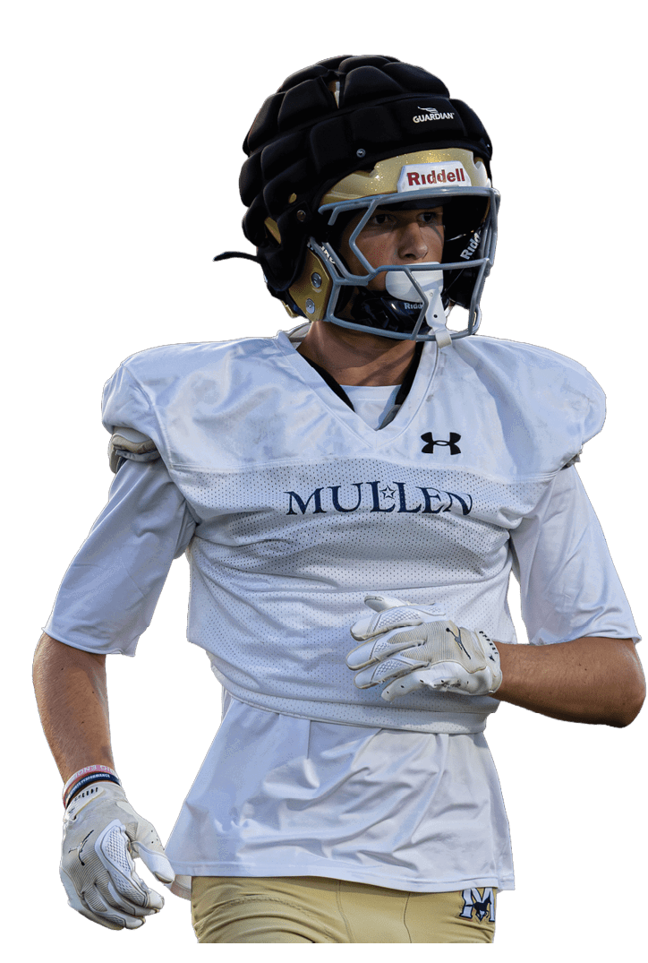 Person wearing a football helmet and white practice jersey with “MUELLER" written on it, standing with hands positioned as if ready to catch or throw a ball. Description generated by AI