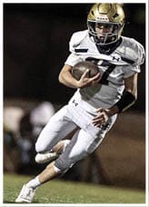 A person wearing a white sports uniform is holding a football tightly while running. Description generated by AI