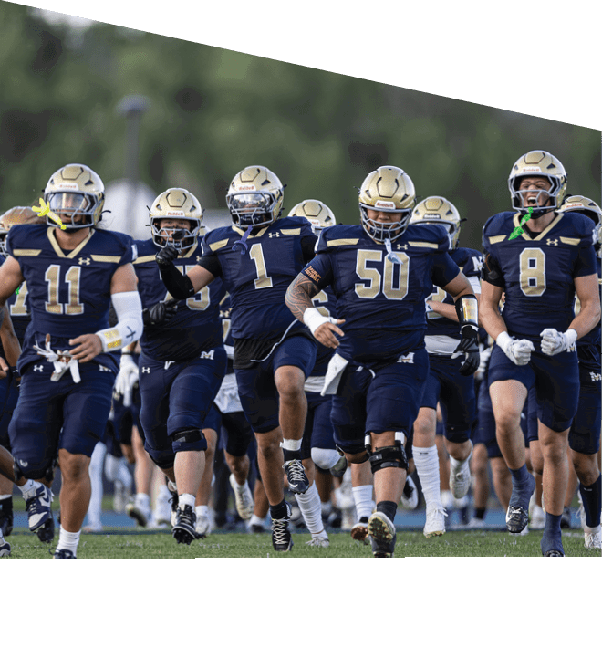 A group of people wearing navy blue football uniforms and gold helmets are running forward on a field. Description generated by AI