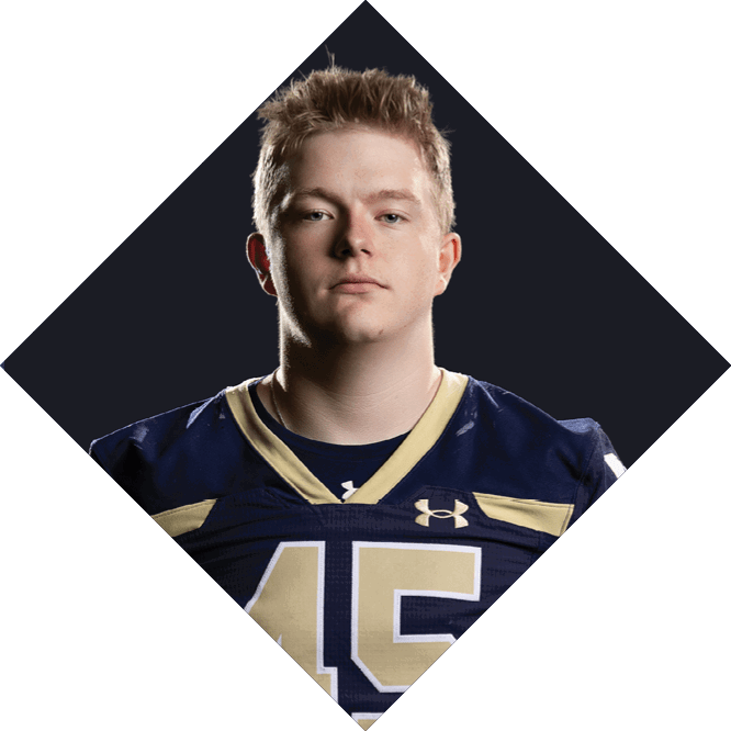 A person with short, light-colored hair wearing a dark blue and gold sports jersey with the number 45 stands against a dark diamond-shaped background. Description generated by AI