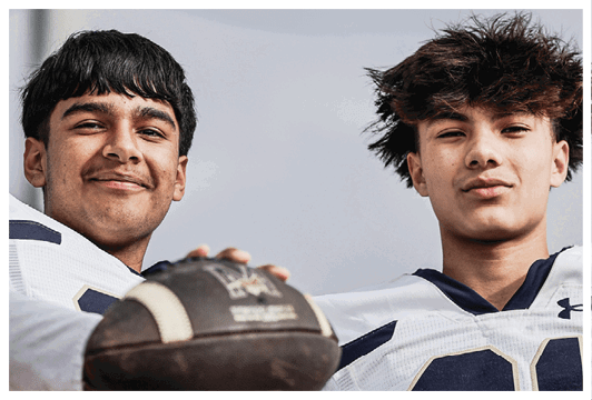 Two men holding a football. Description generated by AI