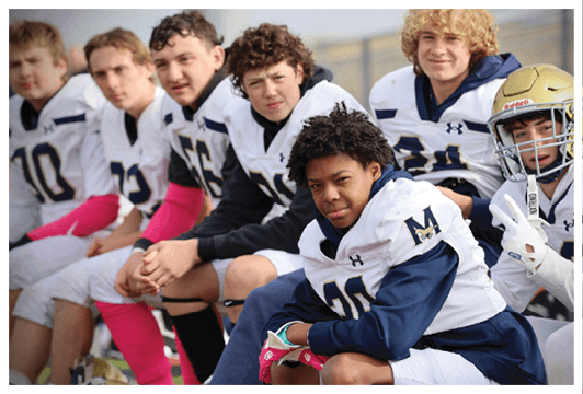 A group of young men wearing football uniforms. Description generated by AI