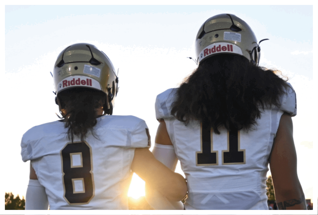 Two football players standing on a field. Description generated by AI
