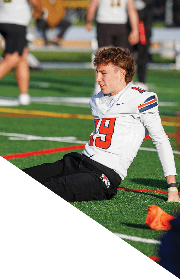 A football player is kneeling on the field, holding his helmet in his hands. AI generated content