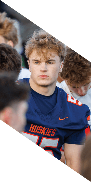 Two football players are on the field, one jumping in the air while the other is running. A referee is also present, watching the play. AI generated content