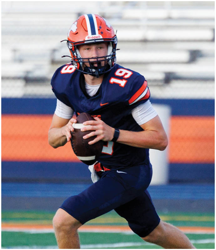 Three football players in blue and white uniforms running on a field. Description generated by AI