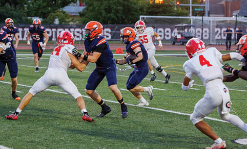 Two men wearing football uniforms are hugging each other on a field. AI generated content