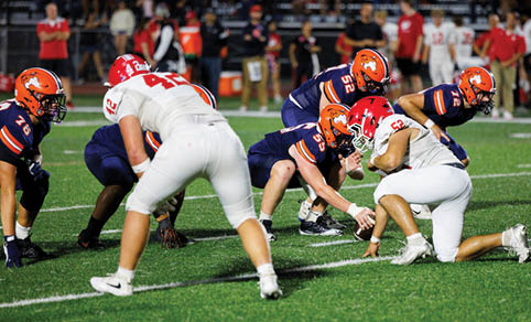 Two men wearing football uniforms are hugging each other on a field. AI generated content