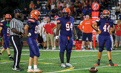 Two men wearing football uniforms are hugging each other on a field. AI generated content