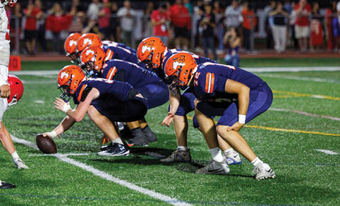 Two men wearing football uniforms are hugging each other on a field. AI generated content