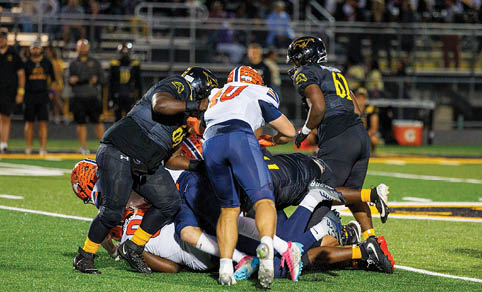 Two men wearing football uniforms are hugging each other on a field. AI generated content
