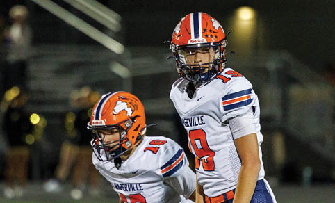 Two men wearing football uniforms are hugging each other on a field. AI generated content