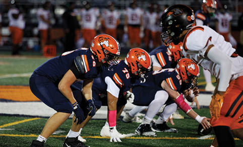 Two men wearing football uniforms are hugging each other on a field. AI generated content