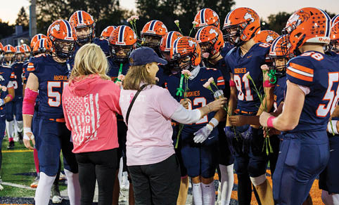 Two men wearing football uniforms are hugging each other on a field. AI generated content