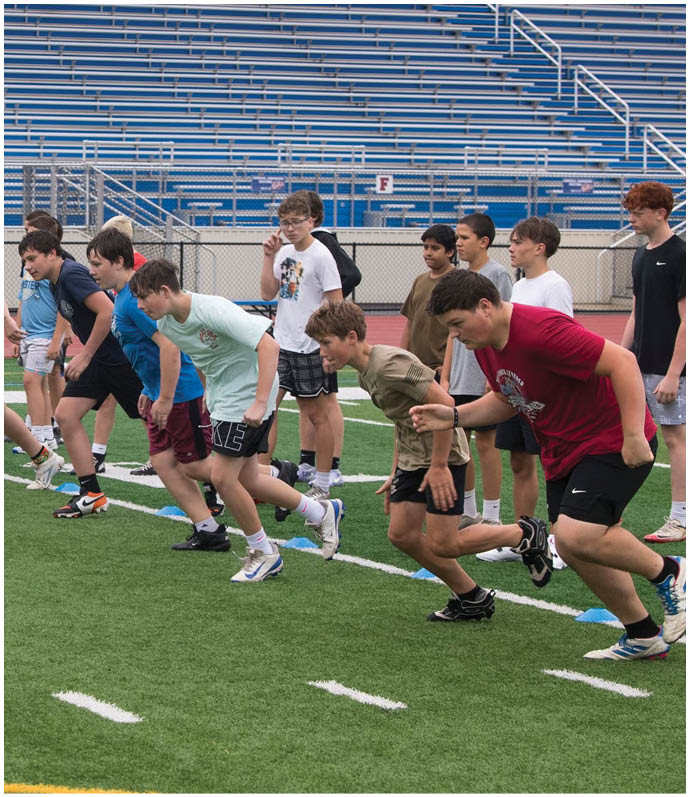 Three football players in blue and white uniforms running on a field. Description generated by AI