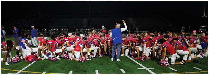 A group of football players on a field. Description generated by AI