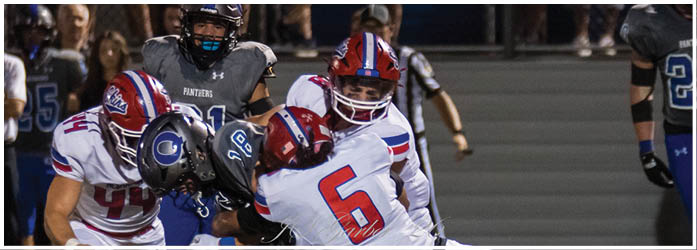 Two people wearing white football jerseys with “Neshaminy" written on them stand closely together, appearing focused and serious. Description generated by AI