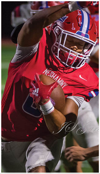 A person wearing a red and white football uniform with the number 57 is running on a football field. Description generated by AI