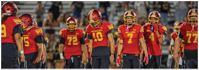A group of football players wearing red and black uniforms. Description generated by AI