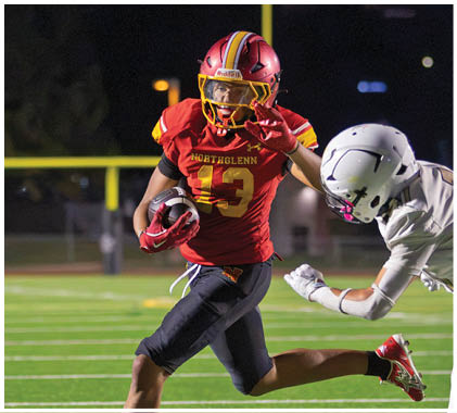 A football player running with a football. Description generated by AI