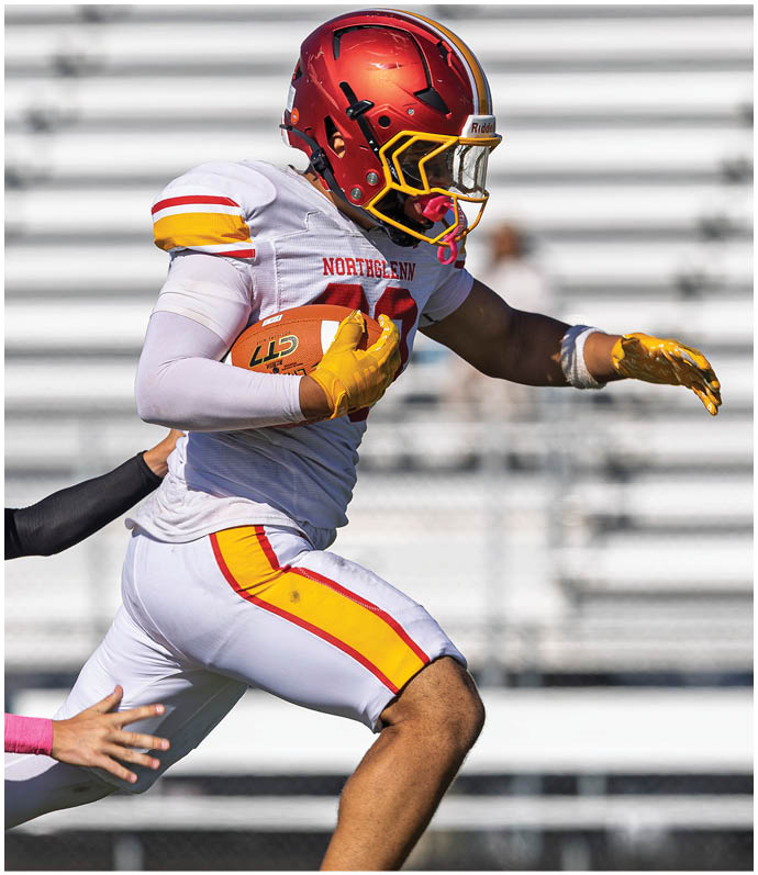 A football player running with a ball. Description generated by AI