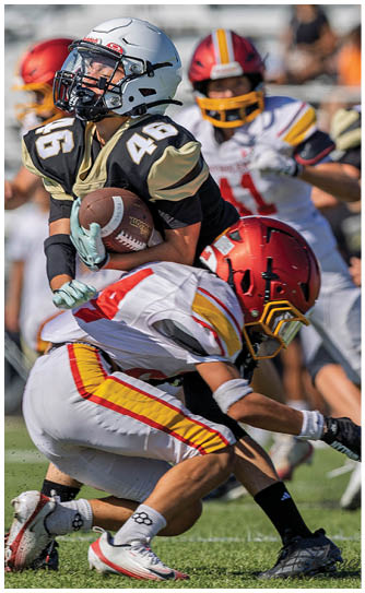A football player in a white jersey is tackled to the ground by another player. Description generated by AI