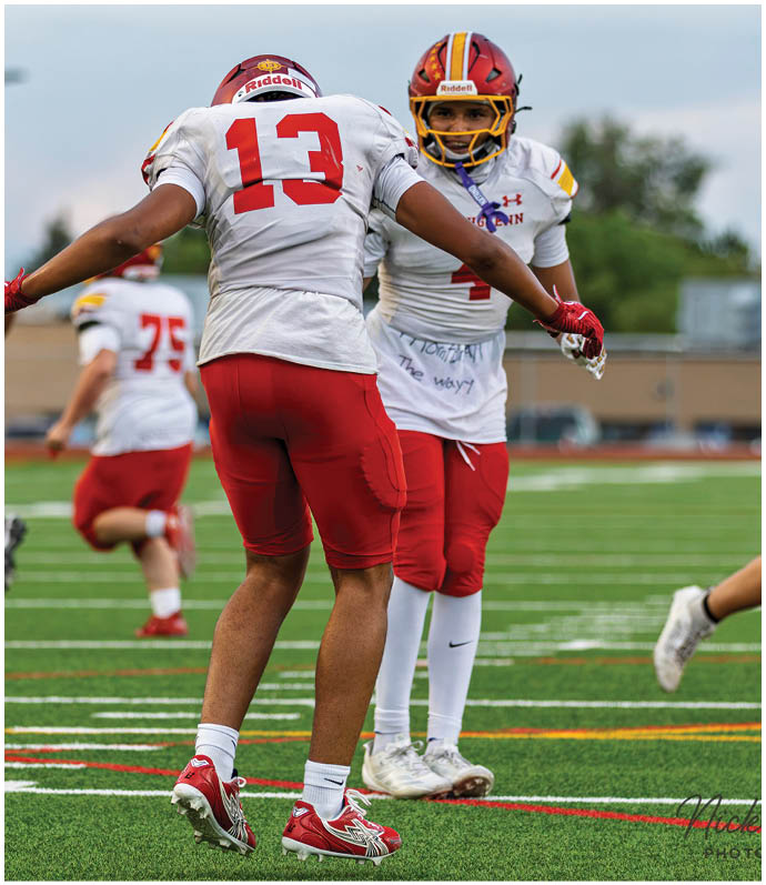 Two football players wearing red and white uniforms celebrating a touchdown. Description generated by AI