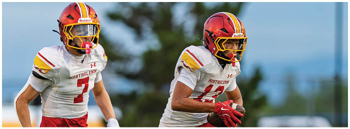 Two football players running on a field. Description generated by AI