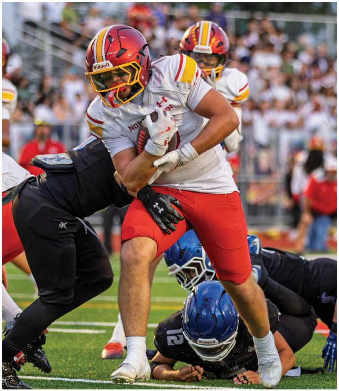 A football player in a red jersey is tackled by another player. Description generated by AI