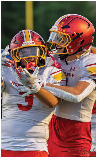 Two football players wearing red and white uniforms. Description generated by AI