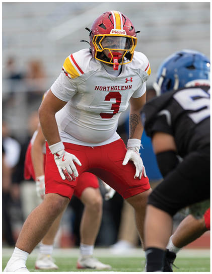A football player wearing a red jersey with the number 3 on it. Description generated by AI
