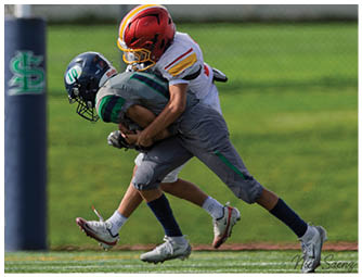 Two boys playing football. Description generated by AI