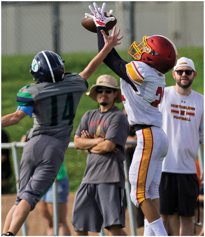 A man wearing a red and yellow jersey is jumping in the air to catch a football. Description generated by AI