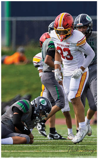 A football player is kneeling on the ground with his hands on his head. Description generated by AI