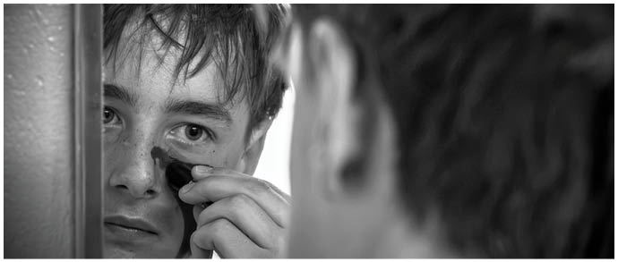A boy is looking at his reflection in the mirror. Description generated by AI